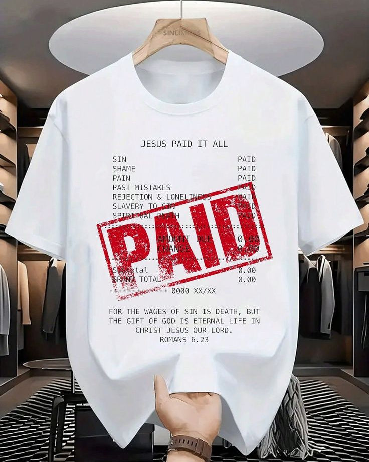 White t-shirt with religious text and 'PAID' stamp in a store setting